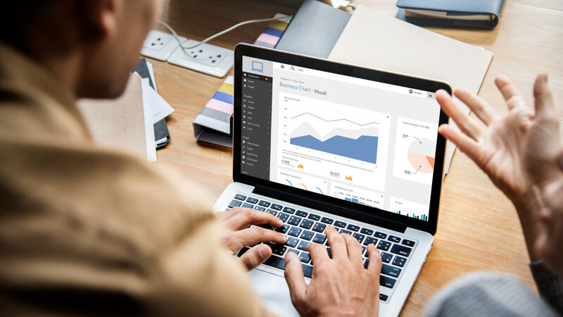 Analyst reviewing analytics dashboard on laptop in office setting